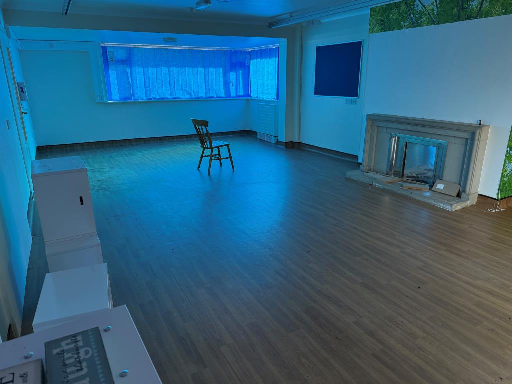Lot: 87 - FORMER NHS PREMISES WITH POTENTIAL FOR DEVELOPMENT - Day room with fireplace and window overlooking front garden